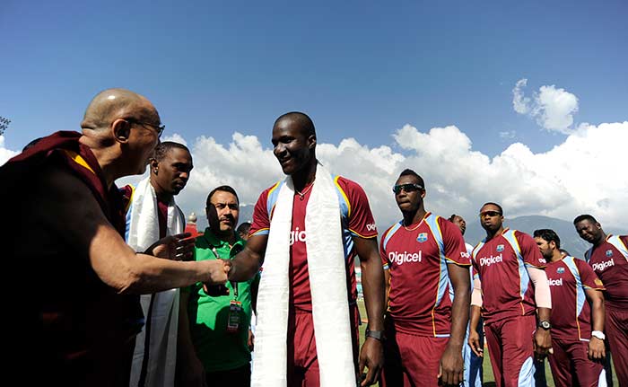 Former captain and star all-rounder Darren Sammy of West Indies greets Dalai Lama as teammates Andre Russell and Kieron Pollard wait for their turn in Dharamsala on Friday.