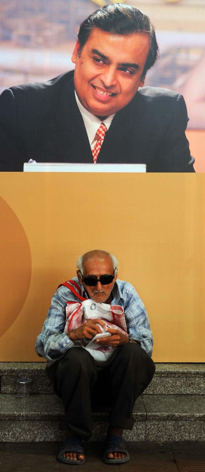 A Reliance shareholder sits underneath a Mukesh Ambani poster during the event. Ambani said Rs 1,000 invested at the time of the initial public offering of the company in 1977-78 has grown to Rs 7.78 lakh today.