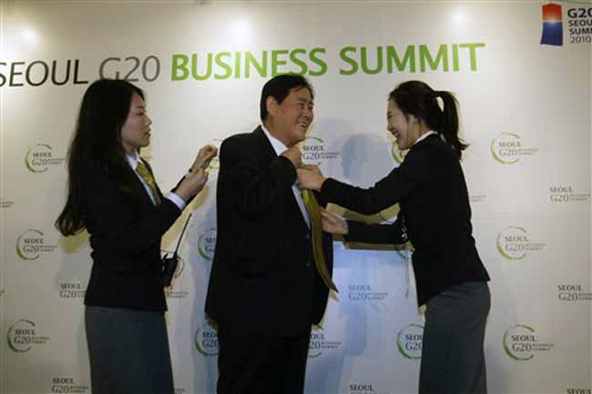 G-20 volunteers help to put a tie on to Choi Kyung-hwan, South Korea's Knowledge Economy Minister, as he arrives to host a reception for the G20 Business Summit. (AP)