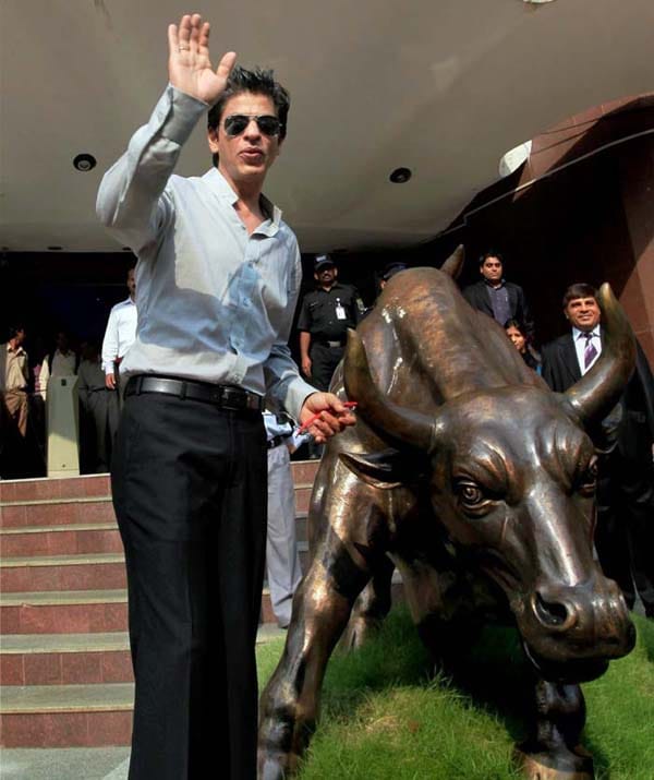 Shah Rukh Khan poses with the bull-statue at Bombay Stock Exchange during listing of the Eros International Media Limited, in Mumbai on Wednesday. (PTI)