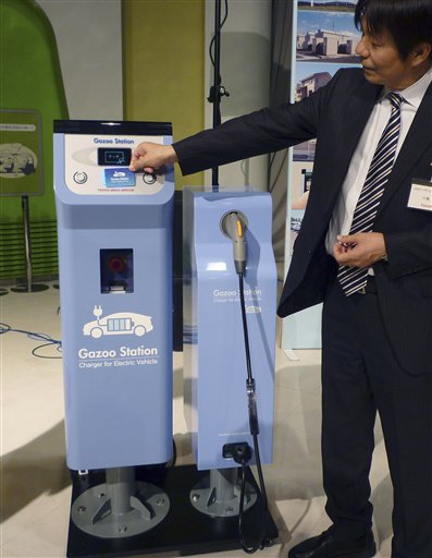 A Toyota employee places a card to start an electric recharging station for plug-in hybrid vehicles during a demonstration of Toyota Smart Center in Tokyo. (AP Photo)