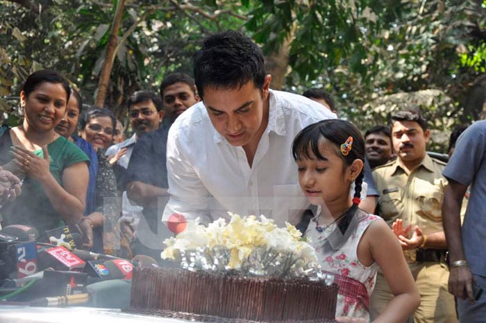 Aamir cuts his birthday cake with a young fan of his.