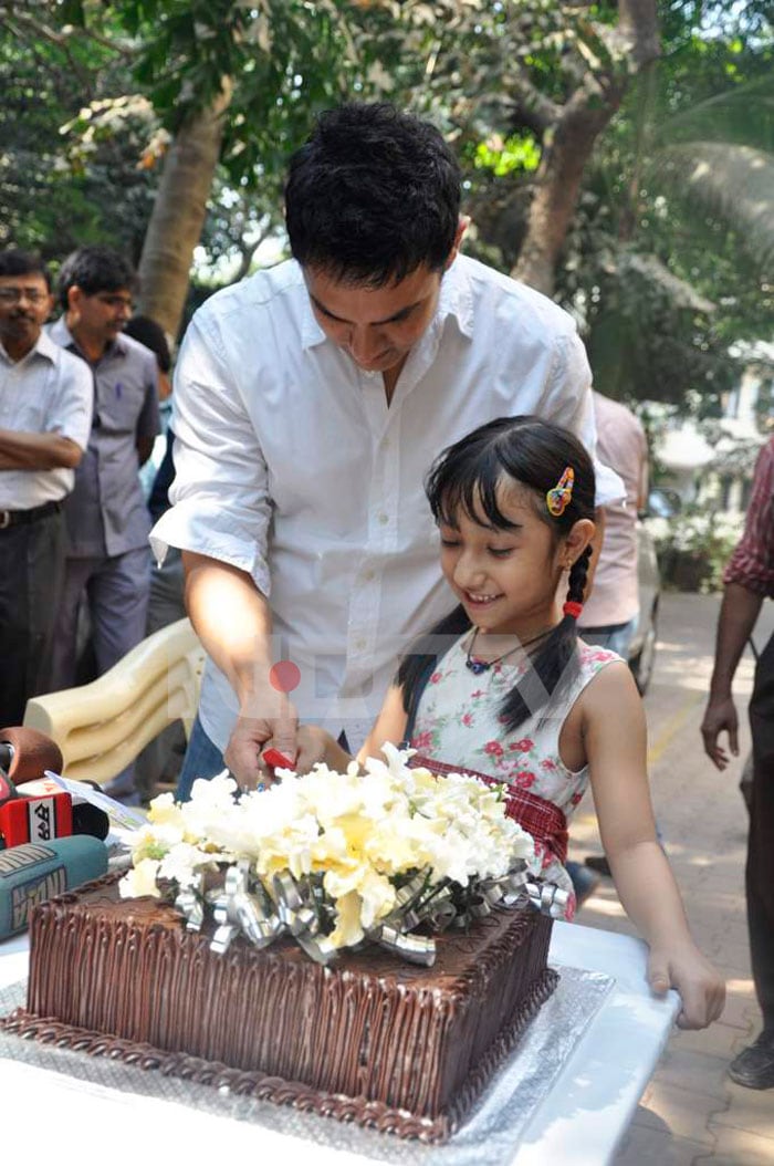 Aamir cuts his birthday cake with a young fan of his.