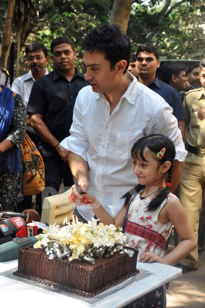 Aamir cuts his birthday cake with a young fan of his.