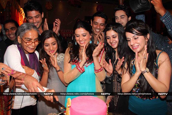 Surekha Sikri cuts the cake while others applaud.