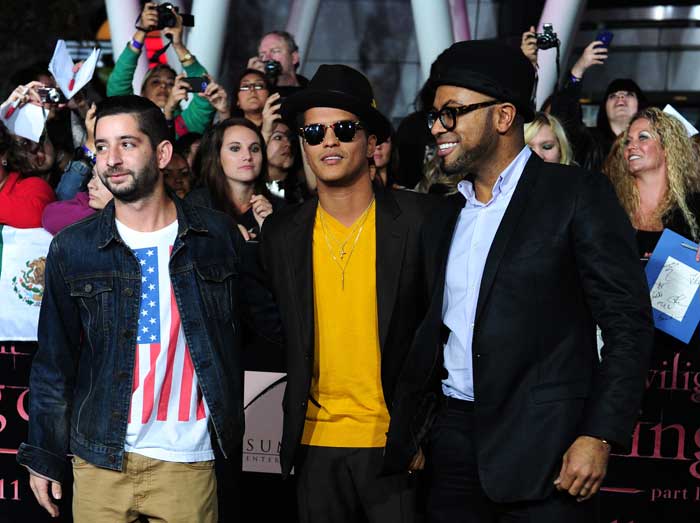 Singer Bruno Mars poses in a brown suit teamed with a yellow T-shirt at the premiere.