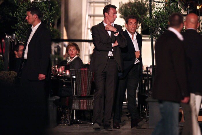 French President Nicolas Sarkozy, center right, is seen surrounded by bodyguards on the set of the movie "Midnight in Paris", directed by Woody Allen, in Paris, Wednesday, July 28, 2010. Sarkozy's wife Carla Bruni Sarkozy acts in the last movie of the U.S director.