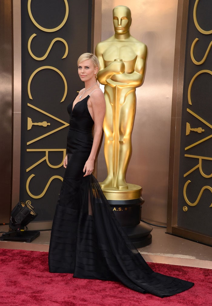 Charlize Theron in Christian Dior: She wore pristine white last year and this year, Charlize was black gold in a dress with a sweeping train.