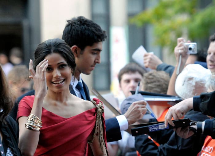 Actor Dev Patel, right, and actress Freida Pinto arrive and autograph items for fans at the premiere of the feature film <i>Miral</i>.