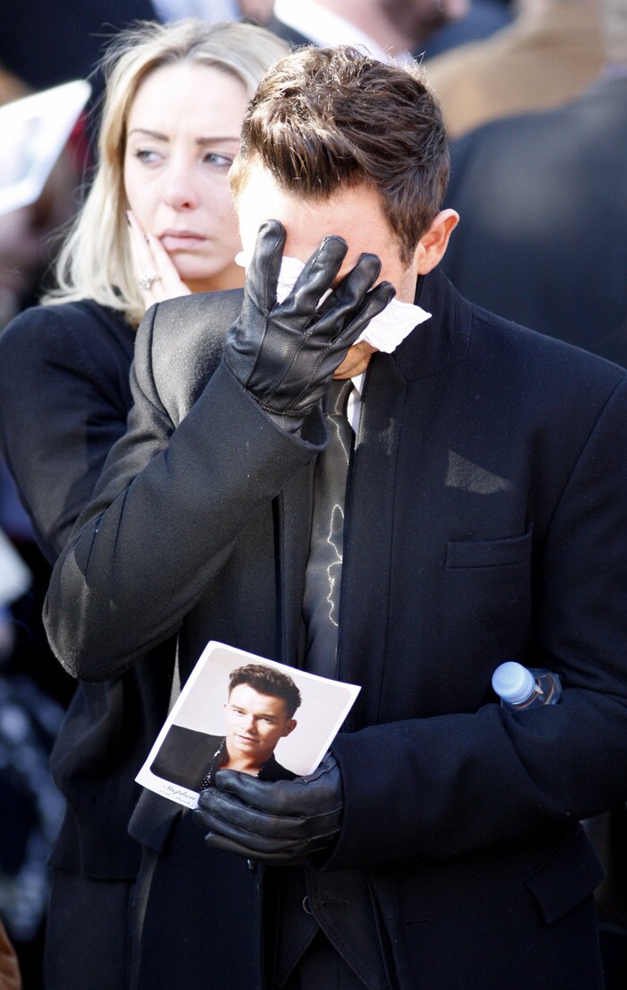 A mourner reacts f during the funeral of Stephen Gately at St. Laurence O'Toole Church, after the funeral service, in Dublin, Ireland, Saturday Oct. 17, 2009. Gately was found dead on Saturday, Oct. 10, 2009, in a house near Port d'Andratx on the western tip of Mallorca. The singer had gone to Mallorca with his partner Andrew Cowles. The two were wed in a civil union in 2006. Autopsy results released on Tuesday showed Gately died of natural causes. Photo of Gately seen on the right. (Photo: AP)