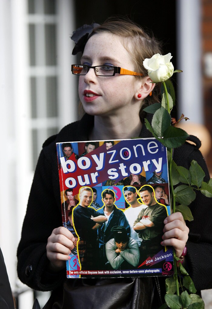 A fan of Irish band Boyzone, watches the funeral of band member Stephen Gately  at St. Laurence O'Toole Church, after the funeral service, in Dublin, Ireland, Saturday Oct. 17, 2009. Gately was found dead on Saturday, Oct. 10, 2009, in a house near Port d'Andratx on the western tip of Mallorca. The singer had gone to Mallorca with his partner Andrew Cowles. The two were wed in a civil union in 2006. Autopsy results released on Tuesday showed Gately died of natural causes. Photo of Gately seen on the right. (Photo: AP)