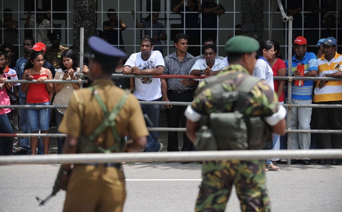 Sri Lankan security personnel stand guard as fans wait to catch a glimpse of Bollywood personalities outside the stadium where a cricket match between Indian Bollywood actors and Sri Lankan cricketers are being held during the three day International Indian Film Academy (IIFA) awards events in Colombo on June 4, 2010.