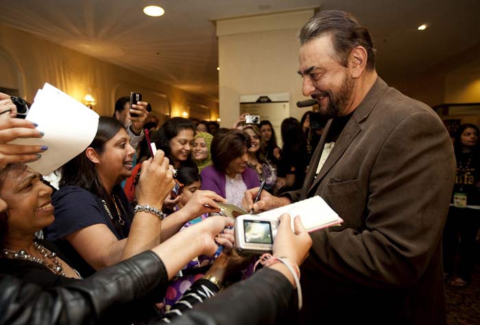 Actor Kabir Bedi signs autographs as he arrives at Toronto.