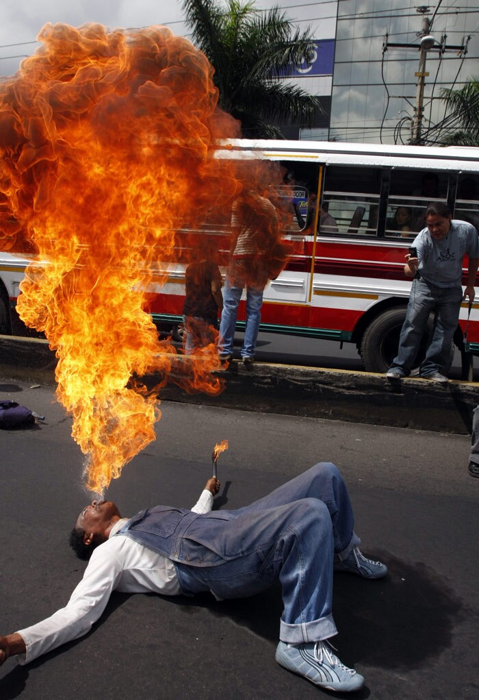 A clown going by the name Ivan performs a fire-spitting act, during a protest of professional clowns against the common practice of armed bandits who pose as clowns and rob people on buses and other forms of public transport, in San Salvador, on Thursday June 10, 2010. The protest was held after two clown impostors killed a passenger last Monday on a public bus during a robbery. (Photo: AP)