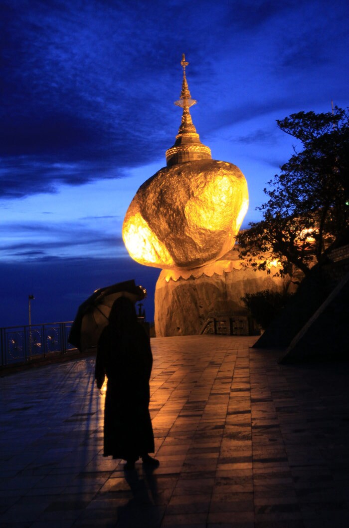 In this photo taken on Monday, June 7, 2010, a devotee prays in the rain at Kyeikhtiyoe Pagoda in Kyeikhto, about 200 kilometers northeast of Yangon, Myanmar. Buddhists believe that two hairs of Lord Buddha are enshrined in the giant stone on which the pagoda was built over 2500 years ago. (Photo: AP)