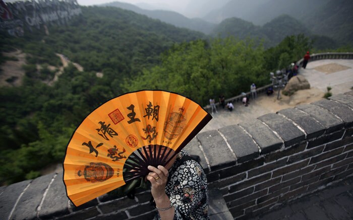 An elderly Chinese woman, uses a hand fan to cool herself up as she rests from walking along part of the Great Wall of China, north of Beijing, China, on Monday, June 7, 2010. (Photo: AP)