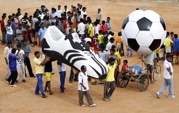 Soccer fans crowd around a giant size soccer shoe before taking part in a procession to celebrate the start of the FIFA World Cup 2010, in Bangalore, on Friday, June 11, 2010. (Photo: AP)