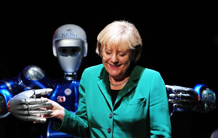 German Chancellor Angela Merkel jokes with 'SpaceJustin', a humanoid space robot, at the International Aerospace Exhibition (ILA) on June 8, 2010 at the Schoenefeld airport in Berlin. The biannual show is the third biggest in Europe after those in Britain and France, was expected to draw more than 1,100 exhibitions from 37 countries. (Photo: AFP)