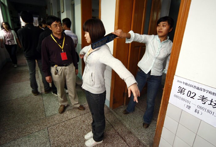 A Chinese teacher checks a student for any hidden electronic devices before she sits for the annual 'Gaokao' or college entrance examinations in Suining, southwest China's Sichuan province on June 7, 2010. Nearly 10 million high school students began sitting for China's make-or-break college entrance exams under tight security following a spate of school attacks and concerns over cheating. (Photo: AFP)