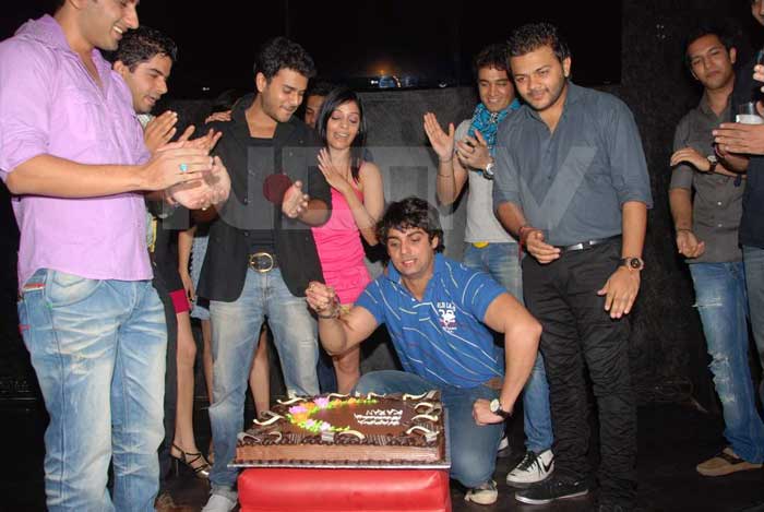 Karan Wahi cuts the birthday cake as his friends cheer on.