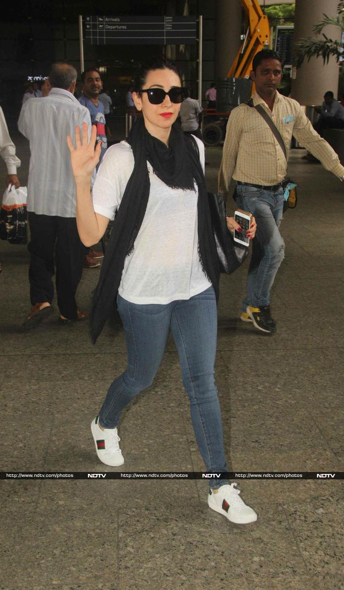 Actress Karisma Kapoor waved for the cameramen. She was seen wearing white top and denims. She topped the look with black scarf and <i>Kala Chashma</i>.