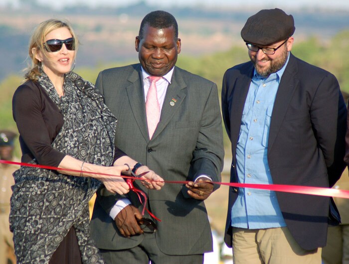US singer Madonna (L) cuts a ribbon next to Malawi?s Education Minister George Chiponda (C) and the co-founder of Raising Malawi Girls Academy, Michael Berg (R) during a ceremony to officially launch the construction work of Madonna's Girls Academy in Lilongwe on October 26, 2009. Madonna broke ground today on a girls academy she is building in Malawi, billed as a "gift" to the country from where she has adopted two children.  (Photo: AFP)