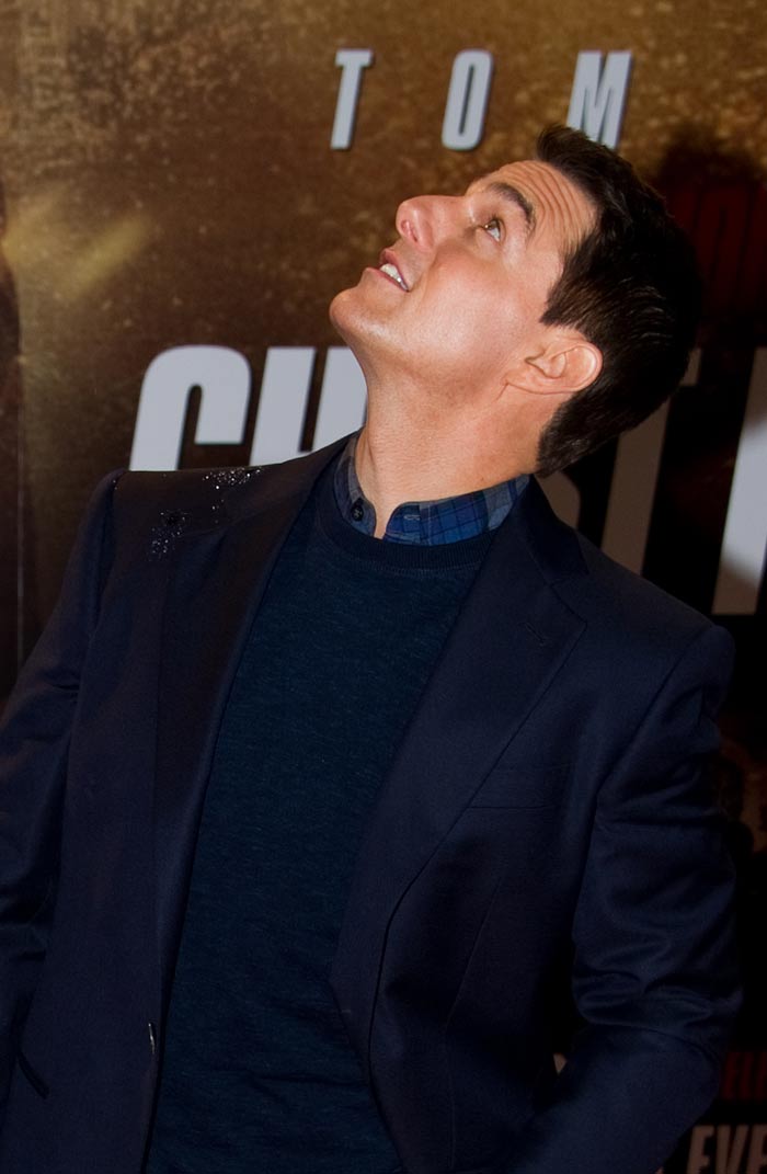 Tom Cruise dodges rain drops as he poses for photographers.