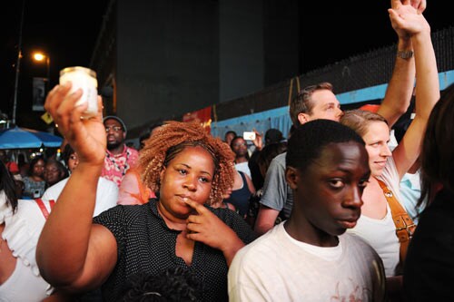 After hearing of the death of pop star Michael Jackson, a woman holds a candle as others sing.