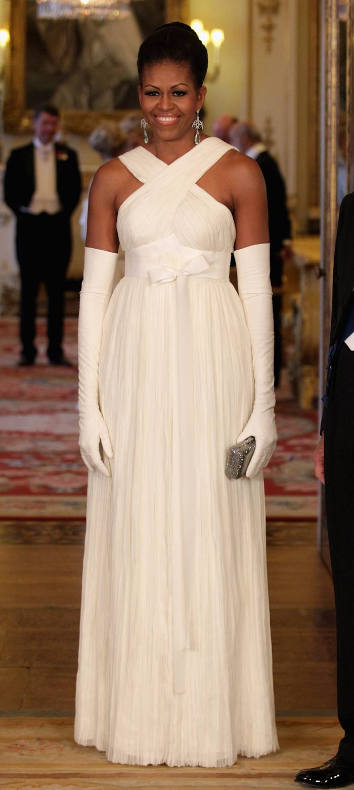 At the Buckingham Palace state banquet hosted by Queen Elizabeth II, Michelle Obama looked elegant in an off-white crisscross gown by Tom Ford with matching gloves, metallic clutch and updo.