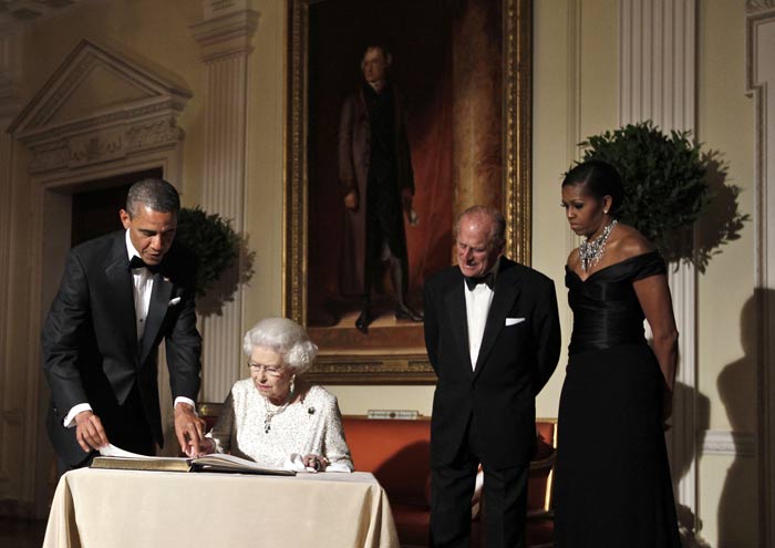 The US President holds open the guest book for Queen Elizabeth II to sign as Michelle Obama and Prince Philip look on after the dinner at Winfield House.