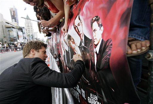 Brad Pitt  draws a moustache on his face on the poster for the film Ocean's 13 during the premiere of of the film at Grauman's Chinese Theater in Los Angeles.