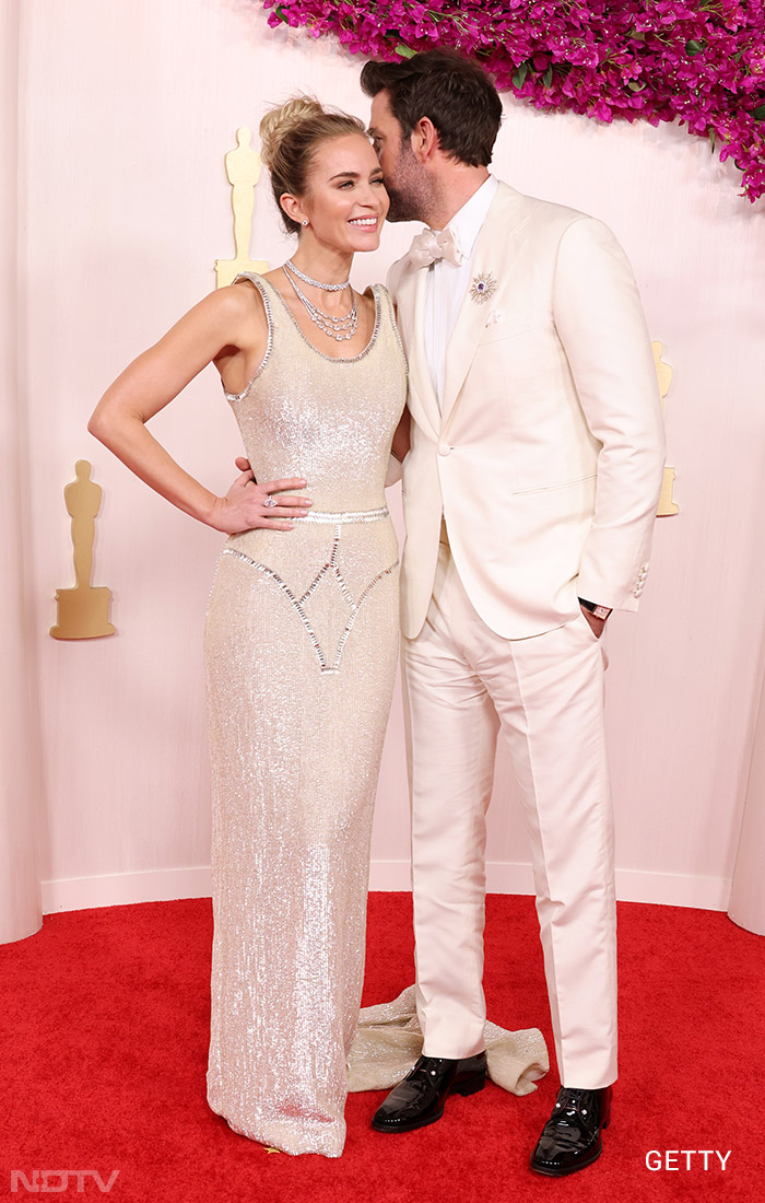 Emily Blunt, stunning in a Schiaparelli gown, was complemented by husband John Krasinski, who opted for a cream tuxedo. (Image courtesy: Getty)