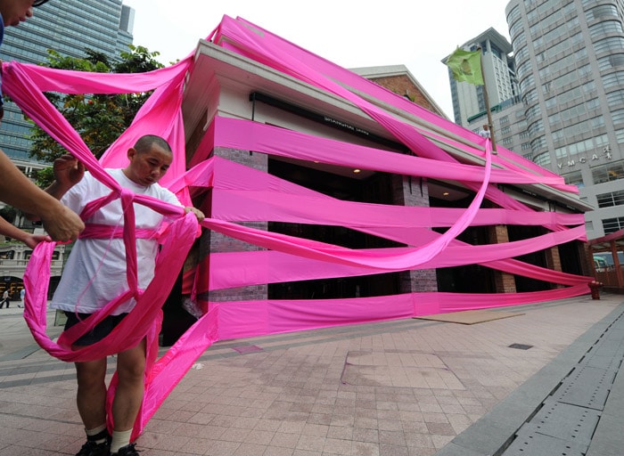 Chinese artist Li Wei performs outside a shop in Hong Kong on May 27, 2010. Li Wei has performed all over the world to communicate his artistic message. His current exhibition is entitled 'Beyond Gravity' dealing with desire for material goods and power. (Photo: AFP)