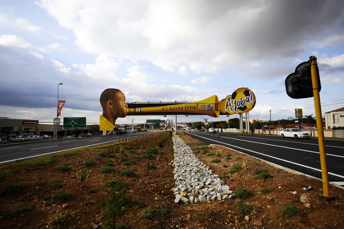 Cars drive under a giant advertising billboard picturing a man blowing a vuvuzela on May 31, 2010 in Polokwane, South Africa. Polokwane is one of the South African city hosting the FIFA World Cup from June 11 to July 11, 2010. (Photo: AFP)