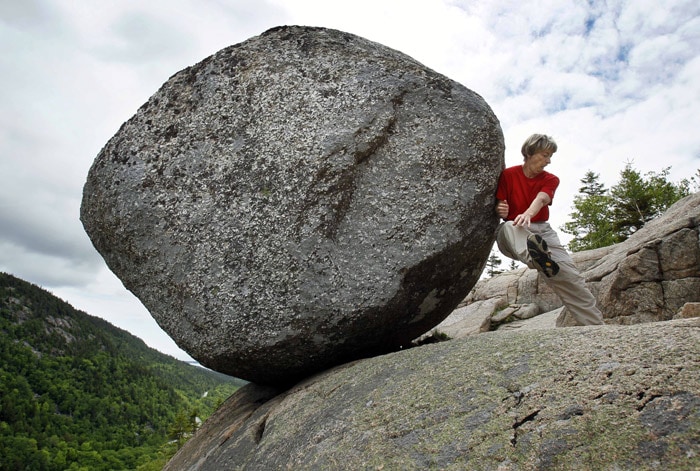 Doris Morgan, of Tampa, Fla., playfully attempts to dislodge the Bubble Rock near the summit of South Bubble Mountain, on Friday, June 4, 2010, in Acadia National Park near Bar Harbor, Maine. Although thousands of hikers have tried, no one yet has been able to budge the glacial erratic. The boulder was deposited on the precipice by a receding glacier about 10,000 years ago. (Photo: AP)