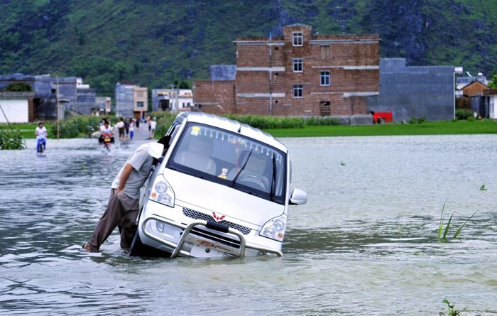 A man pushes a vehicle in flood in Yao Ethnic Autonomous County of Du'an in south China's Guangxi Zhuang Autonomous Region, on June 2, 2010. The rainstorms had damaged 3,260 homes and 103,450 hectares of crops, according to Guangxi's Civil Affairs Department. (Photo: AFP)