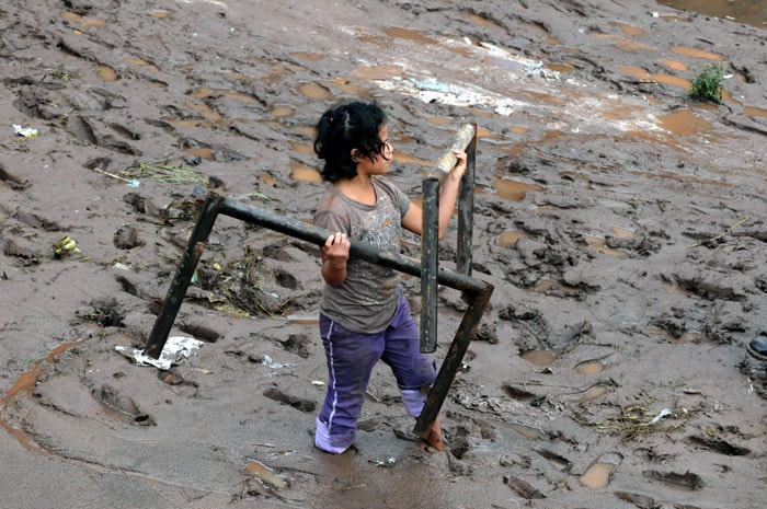 A girl recovers objects from the mud outside La Isla market, after it was flooded by triopical storm Agatha in Tegucigalpa, on June 1, 2010. Seventeen people were killed in Honduras as a result of tropical storm Agatha, according to official figures. (Photo: AFP)