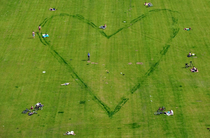 People sitting around the contour of a heart scratched into the lawn enjoy the sun on June 6, 2010 in the center of Berlin. Spring brought temperatures up to 29 degrees Celsius to the German capital. (Photo: AFP)