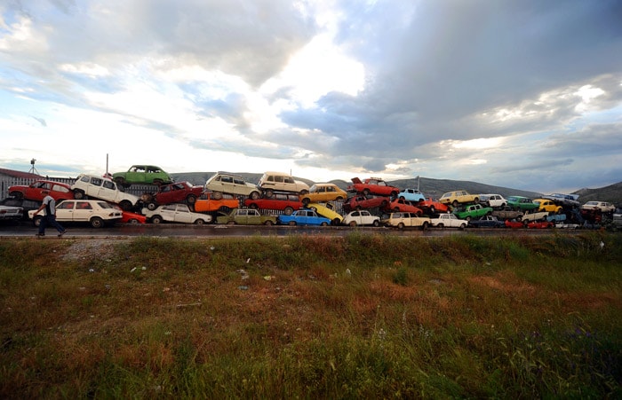 A man walks in front of an old car dump on a road near Skopje on June 2, 2010. (Photo: AFP)