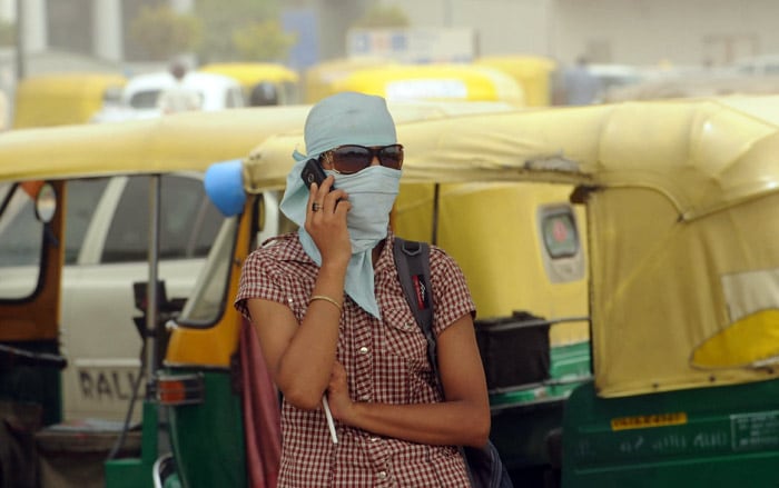 A woman with her face covered against a dust storm speaks on a mobile phone in New Delhi on June 3, 2010. (Photo: AFP)