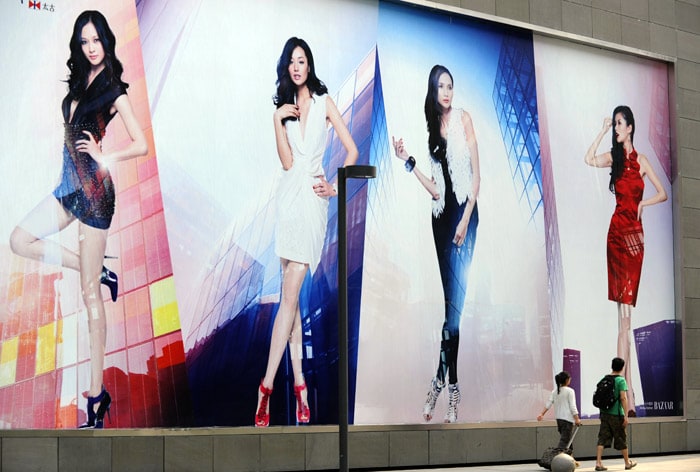 Two shoppers walk past advertisements for fashion goods outside a shopping mall in Beijing on June 3, 2010. China's inflation could top the government's three percent target in 2010 due to price pressures in the second half of the year, a central bank adviser said, raising pressure for a possible rate hike. (Photo: AFP)