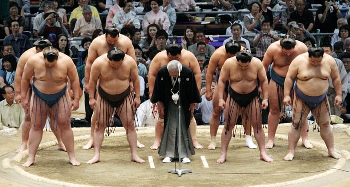 Hiroyoshi Murayama, in kimono, acting chairman of the Japan Sumo Association, and top sumo wrestlers bow to spectators in apology on the opening day of a sumo tournament at Nagoya, central Japan, on Sunday July 11, 2010. The Nagoya Grand Sumo Tournament opened under a cloud of controversy Sunday as Japan's national sport grapples with a widespread betting scandal. (Photo: AP)