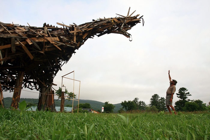 In this photo taken on Friday, July 9, 2010, Brian Boland, 52, a former teacher, hot-air balloon designer and balloon pilot who runs the rural Post Mills Airport in Thetford, Vt., stands with his "Vermontasaurus," where the 25-foot tall oddity thrown together with scrap wood now faces opposition from a few neighbors and regulatory challenges from government entities that he fears could force him to dismantle what was built with the help of some area residents as an artistic collaboration. (Photo: AP)