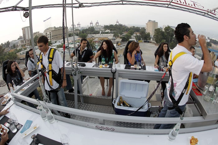 Twenty two men and women suspended 50 meters over a parking lot, enjoy their meal at "Dinner in the Sky" on July 10, 2010, in Beirut, where guests sit harnessed around a dining table lifted up into the air by a crane and served a full diner with drinks. (Photo: AFP)