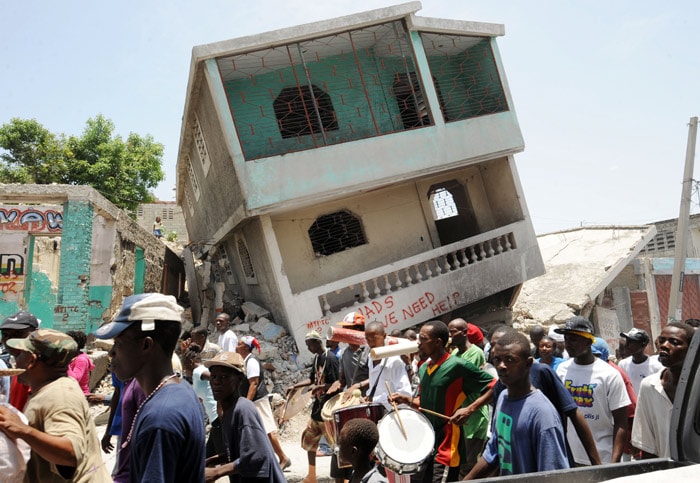 Haitians demonstrate in front of an earthquake destroyed house on July 13 2010 to demand the resignation of President Rene Preval and the CEP (conseil electoral provisoire) in Port-au-Prince. Haitians marked a sad anniversary on July 12, mourning the hundreds of thousands killed six months ago in a massive earthquake and eyeing a precarious future amid the slow trickle of aid. (Photo: AFP)