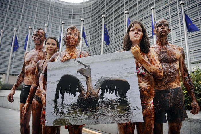 This handout pictured provided by Greenpeace shows Greenpeace activists with oily skin who protested on Wednesday, July 14, 2010, against deep sea drilling for oil in front of the EU ministry in Brussels, where energy commissioner Guenther Oettinger met with managers of the oil industry to discuss consequences from the oil catastrophe in Gulf of Mexico. (Photo: Greenpeace)