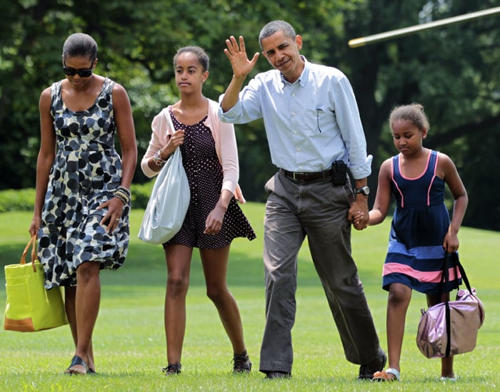 President Barack Obama waves to media as he and first lady Michelle Obama, left, and their children Sasha and Malia Obama, second left, arrive on the South Lawn of the White House in Washington after a weekend vacation on Mount Desert Island in Maine, on Sunday, July 18, 2010. (Photo: AP)