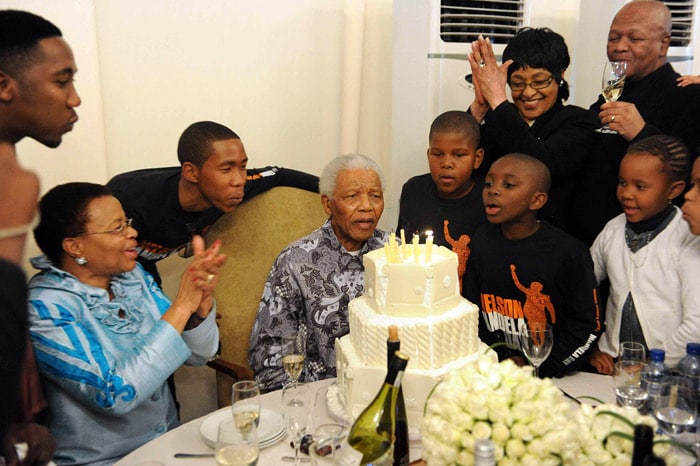 Nelson Mandela (C) blows out the candles on a cake on his 92nd birthday celebrations on July 18, 2010 as he is surrounded by his wife Graca Machel (L), grandchildren and Winnie Madikizela-Mandela (top 2R) at his home in Johannesburg. South Africa's President Jacob Zuma hailed Nelson Mandela as a symbol of unity as the anti-apartheid icon celebrated his 92nd birthday. The day marked the first United Nations recognised Nelson Mandela International Day, aimed at promoting community service among nations. (Photo: AFP)