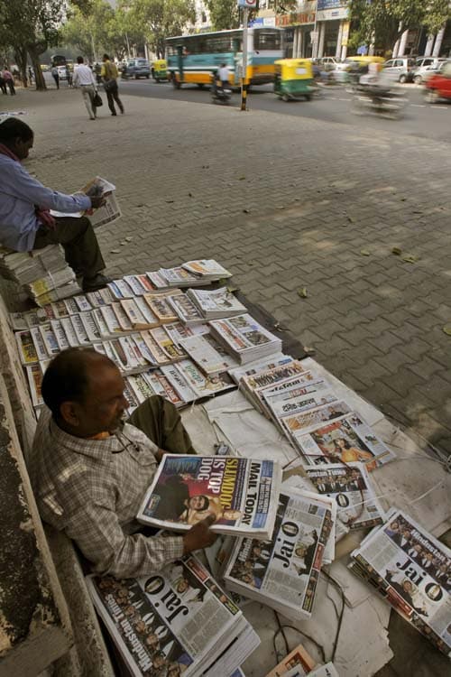 A roadside newspaper vendor arranges newspapers carrying headlines of A R Rahman's success at the Oscars.