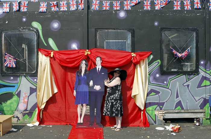 A woman poses for a photograph besides a cardboard cutout the new Duke and Duchess of Cambridge.